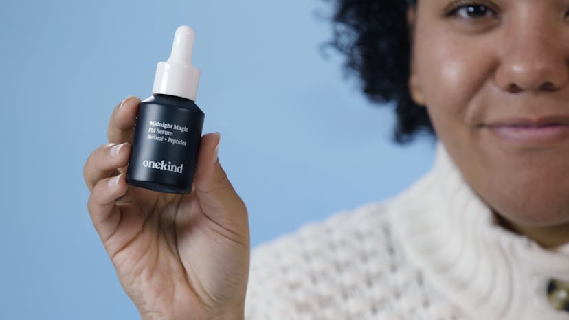 A woman with black and curly hair holding an oil package for dry skin